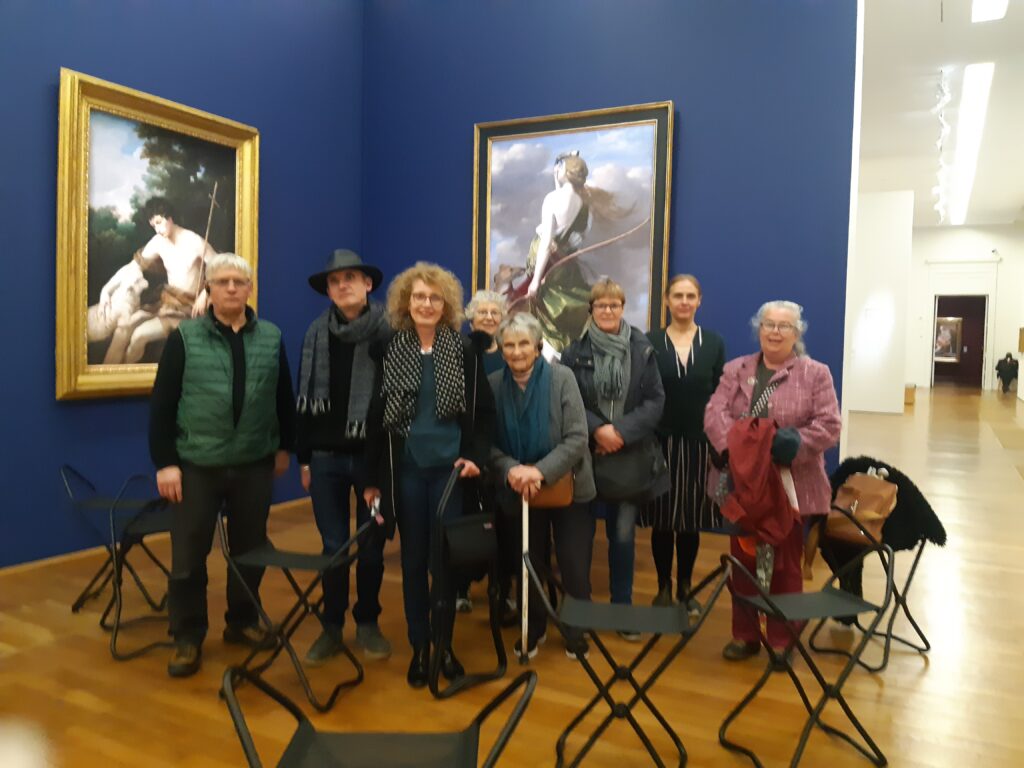 Dans le musée d'arts de Nantes, les 8 personnes de la clissaa avec la m"médiatrice culturelle posent devant deux tableaux.