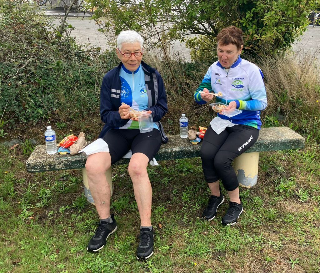 Marie Thé et Annick profitent de la pause déjeuner , assises sur un banc, elles mangent avec appétit.
