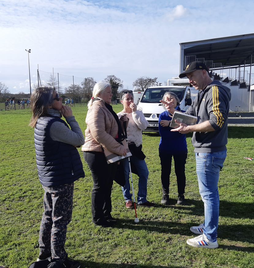 On voit Céline, Stéphanie, Danielle et Emilie écouter les instructions de Jérémy qui leur explique ce qu'est une mêlée