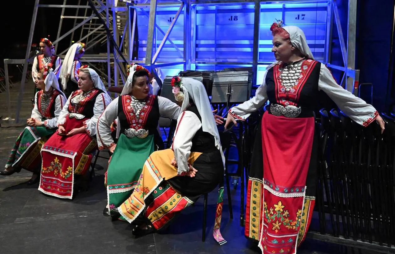 Les choristes avant l'entrée en scène, on voit les couleurs des tabliers correspondant aux registres de voix. Rouge : soprani, jaune : alti, vert : basses